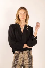 Blusa negra de mangas largas con puños abotonados, escote en V y corte holgado.