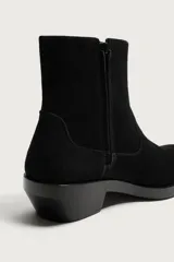 Bota estilo cowboy fabricada en piel con acabado serraje y parte superior lisa. Cuenta con horma cuadrada, cierre mediante cremallera lateral y suela con ligero tacón.
