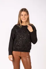 Sweater negro de punto con diseño frontal texturizado y apliques de lentejuelas brillantes. Presenta cuello redondo, mangas largas y puños acanalados.