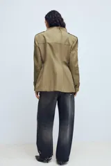 Chaqueta de estilo militar en color beige, con cuello subido, cierre frontal de botones, bolsillos de plastrón con solapa en el frente y detalle de hombreras con trabillas.