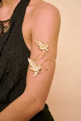 Brazalete dorado para el brazo, diseño abierto decorado con dos figuras de palomas en relieve.