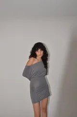 Vestido corto de lycra color bordó, con diseño de hombros descubiertos, manga larga tipo dolman y fruncido lateral que aporta un ajuste ceñido al cuerpo.