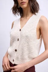 Chaleco de punto color marrón, con escote en V y cierre frontal con botones dorados.