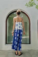 Top de escote recto con tirantes finos ajustables, estampado con motivos marinos de peces y conchas en color azul sobre fondo blanco. Presenta detalle de botones decorativos en el frente y aberturas en el bajo.
