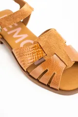 Sandalias planas de cuero color caramelo, con tiras entrelazadas en la parte delantera y tira ajustable con hebilla metálica en el tobillo.