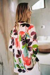 Camisa satinada de manga larga con cuello solapa y cierre frontal con botones, con un colorido estampado floral de estilo acuarela sobre fondo beige.