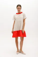 Vestido corto de algodón a rayas horizontales color beige, con cuello redondo negro y falda negra de lino.