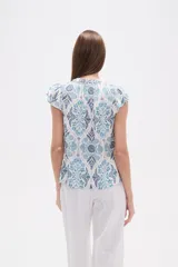 Blusa de rayón con estampado floral en tonos azules y celestes sobre fondo blanco. Presenta cuello en V, botones frontales y mangas cortas con frunces en los hombros.