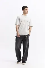 Remera de manga corta color verde salvia, con cuello redondo y un estampado gráfico en la espalda que incluye tipografía en rojo y blanco, y fotografías en blanco y negro.