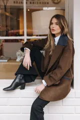 Tapado de paño de lana color marrón con silueta levemente oversize y hombro caído. Presenta doble abotonadura, solapas amplias y un detalle de contraste en el cuello. Incluye ajuste en los puños de las mangas.