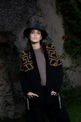 Saco tejido de punto con diseño de guarda inca en la parte superior. Presenta bolsillos frontales con detalles de tiras de cuero y flecos. De corte recto y largo medio, con terminaciones en tejido acanalado.