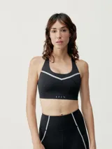 Top deportivo negro de alta sujeción con tirantes regulables cruzados y cierre ajustable en la espalda. Tejido Shape_Tech con tecnología performance y cinta reflectante.