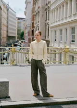 Cardigan de punto color crema con cuello camisero, cierre frontal de cremallera y cinturón integrado con hebilla a la cintura.