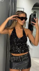 Top halter negro con acabado de lentejuelas brillantes y escote en V pronunciado.