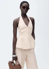 Chaleco color crema con cuello halter y peplum. Cierre frontal con botones.