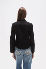 Camisa de algodón negra, de corte entallado, con cuello clásico y cierre frontal de botones.