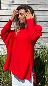 Sweater de punto color rojo, con diseño oversize, cuello redondo, mangas largas con puños acanalados y aberturas laterales en el ruedo.