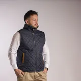 Chaleco negro capitoneado con cuello alto y cierre frontal con botones a presión.