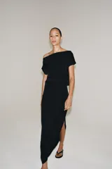 Vestido midi negro confeccionado en hilatura de viscosa, de diseño satinado y corte asimétrico con escote fluido y manga sisa. Presenta bajo acabado en línea evasé y cierre lateral con cremallera oculta en costura.