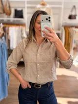 Camisa de algodón con textura geométrica en relieve, cuello camisero, cierre frontal con botones y bolsillo delantero. Presenta mangas largas con puños ajustables.