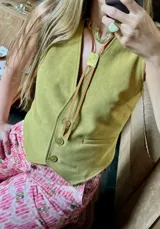 Corbatín de cuero sintético marrón con tiras finas y aplique metálico dorado.