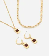 Conjunto de bijouterie color dorado, compuesto por collares de cadena y eslabones, y caravanas de argolla con dijes rectangulares colgantes con aplique de resina burdeos.