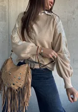 Sweater de punto color beige, con cuello redondo y mangas largas abullonadas. Presenta detalles bordados con lentejuelas y perlas en los hombros y parte superior de las mangas.