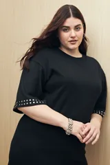 Vestido corto negro de punto, con mangas cortas y apliques de tachas plateadas en los puños.