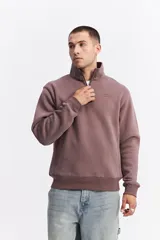 Buzo de algodón con medio cierre frontal y cuello alto. Presenta puños y ruedo acanalados, con un pequeño logo bordado en el pecho.