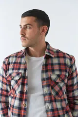 Sobrecamisa de algodón a cuadros color ladrillo, con interior de corderito, cierre con botones, bolsillos tipo cartera y logo en goma. El modelo usa talle M.