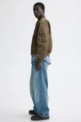 Campera bomber de nylon levemente acolchada, con cuello, puños y bajo acanalados. Presenta cierre frontal, bolsillos laterales con botón a presión y un bolsillo con cierre en la manga.