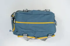 Bolso deportivo color rosa con detalles en beige y gris. Tiene doble asa de mano y correa de hombro ajustable. Cuenta con dos bolsillos frontales con cierre y logo de la marca en la esquina inferior derecha.