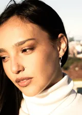 Par de aros dorados tipo argolla con incrustaciones de circonitas y dije colgante de rayo con circonitas.