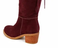Bota de caña alta color suela, confeccionada en cuero napa, con diseño de caña caída y ajuste mediante cordones en la parte superior. Presenta un taco cuadrado foliado de 4,5 cm y suela de goma antideslizante.