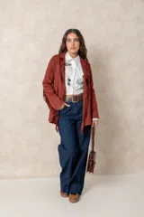 Chaqueta de gamuza color terracota con diseño de flecos en el frente y las mangas. Presenta cuello solapa, cierre frontal y bolsillos delanteros.