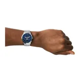 Reloj analógico Fossil Neutra con caja de acero inoxidable de 44 mm, esfera azul con subesferas multifunción y fase lunar, y pulsera de eslabones de acero plateado.