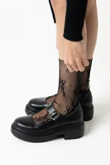 Mocasín negro de cuero con hebilla plateada y suela track.