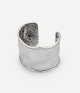 Pulsera rígida de metal plateado con diseño orgánico y superficie martillada de textura irregular.