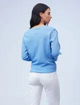 Blusa tejida color celeste con lurex, de manga larga con aberturas y apliques de brillo. Ruedo anudado.