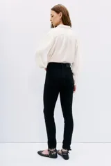 Jean slim negro de tiro medio-alto, con calce al cuerpo y pierna semi-recta. Presenta detalles de hotfix en los bolsillos delanteros y en los puños.