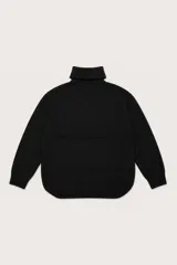 Polera de punto color negro con cuello alto, diseño de corte holgado y ruedo asimétrico con detalle de costura frontal.