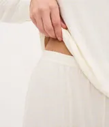 Pijama largo de mujer confeccionado en tejido peach touch, compuesto por una blusa de cuello redondo y manga larga con pequeño bordado en el pecho, y un pantalón con cintura elástica. Presenta un sutil estampado de cuadros.