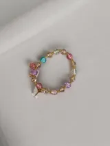 Pulsera elástica compuesta por cuentas de cristal facetado en diversos colores y tonos pasteles, con un dije central en forma de mariposa de material traslúcido.