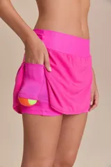 Pollera deportiva color rosa fucsia, con estampado en relieve de texto. Es de corte corto con ruedo redondeado y cuenta con shorts internos.