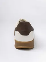 Championes urbanos de diseño minimalista en color blanco, con detalle de talón en color marrón oscuro y suela de goma color caramelo.