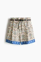 Short holgado de mezcla de lino, con estampado paisley en tonos beige, azul y amarillo, cintura elástica con pliegues, bolsillos laterales al bies y una franja azul con diseño floral en el ruedo. Incluye un cinturón trenzado fino con hebilla metálica.
