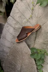 Bolso tipo tote de cuero marrón oscuro, con diseño minimalista, costuras reforzadas con remaches metálicos y correas largas para llevar al hombro.