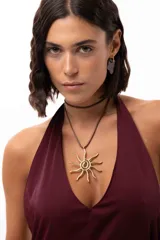 Collar con dije de sol elaborado artesanalmente en bronce, con diseño de rayos en alambre. Presenta un tiento sintético regulable que permite ajustar el largo y utilizarlo de forma doble.