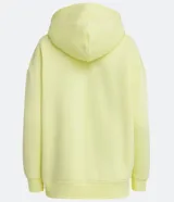 Buzo amarillo de algodón, corte alargado, con capucha, cordón ajustable y bolsillo tipo canguro.