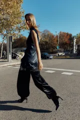Vestido corto de cuello subido y sin mangas, confeccionado en tejido satinado. Presenta un detalle de fruncido lateral con abertura frontal y aplicación de encaje en el bajo.